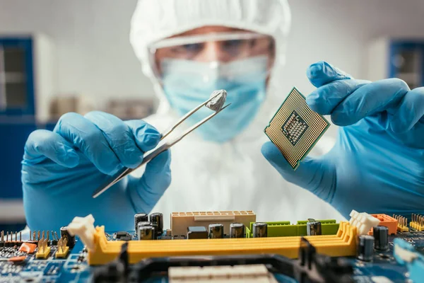 Selective focus of engineer holding small stone with tweezers and microchip near computer motherboard — Stock Photo