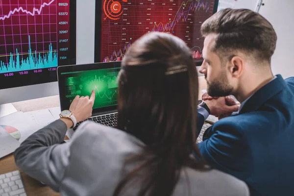 Enfoque selectivo de los analistas de datos que trabajan con gráficos en monitores de computadora en la tabla - foto de stock