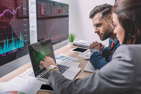 Vue latérale des analystes de systèmes informatiques utilisant des graphiques sur des écrans d'ordinateur pendant qu'ils travaillent au bureau — Photo de stock