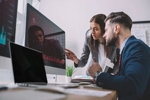 Selektiver Fokus von Informationssicherheitsanalysten, die während ihrer Arbeit im Büro Diagramme auf Computermonitoren verwenden — Stockfoto