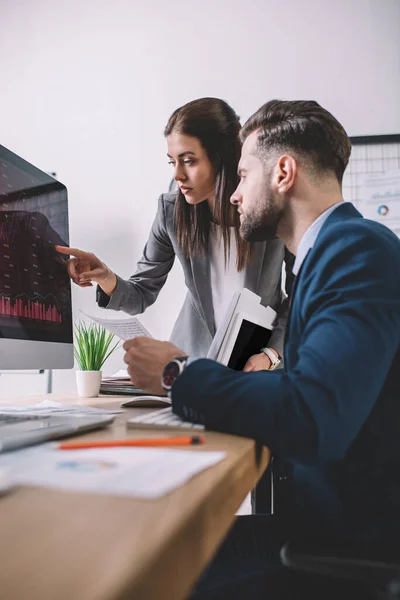 Enfoque selectivo de los analistas de seguridad de la información que trabajan con gráficos en el monitor de computadora en la tabla - foto de stock