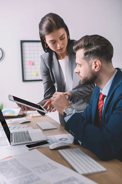 Selective focus of computer systems analyst holding digital tablet near colleague at table — Stock Photo