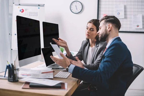 Selective focus of data analysts calculating risks while working with computers and papers in office — Stock Photo