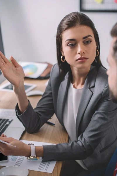 Selective focus of computer systems analyst looking at colleague near papers with carts on table — Stock Photo