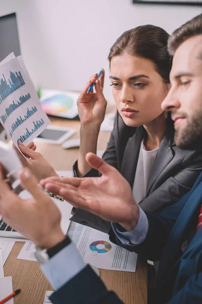 Concentration sélective des analystes de systèmes informatiques utilisant un smartphone et des graphiques pendant qu'ils travaillent au bureau — Photo de stock