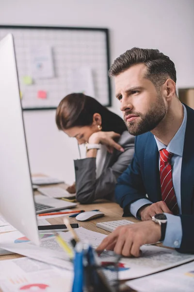 Concentration sélective des analystes de données travaillant avec des papiers et des appareils numériques à la table dans le bureau — Photo de stock