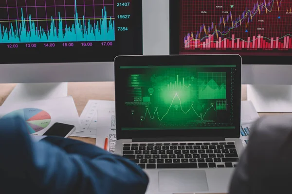 Vista ritagliata di analisti di dati che lavorano con grafici su monitor di computer alla tabella — Foto stock