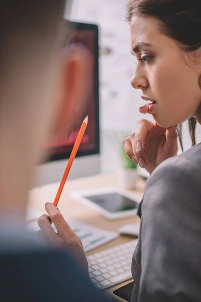 Selektiver Fokus des Datenanalysten mit Bleistift, während er mit dem Kollegen am Tisch arbeitet — Stockfoto