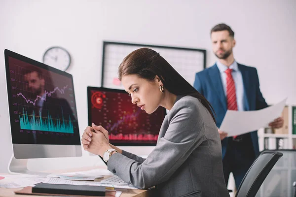 Selective focus of computer security analysts working with papers and charts on computer monitors in office — Stock Photo