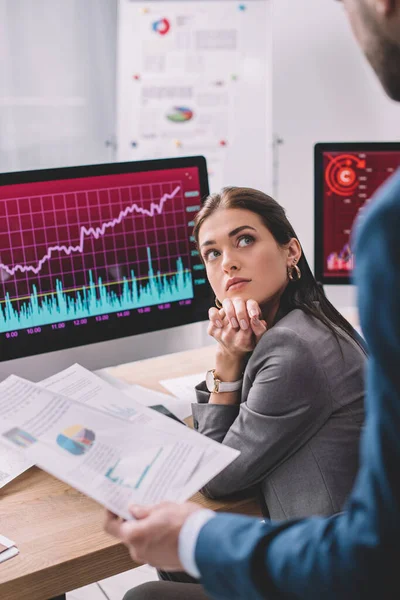 Selective focus of data analyst looking at colleague holding papers with graphs in office — Stock Photo
