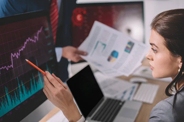 Selektiver Fokus des Informationssicherheitsanalysten, der auf Diagramme am Computermonitor in der Nähe des Kollegen zeigt, mit Papieren in grau isoliert — Stockfoto