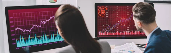 Concentration sélective des analystes de données travaillant avec des graphiques sur des écrans d'ordinateur au bureau, prise de vue panoramique — Photo de stock