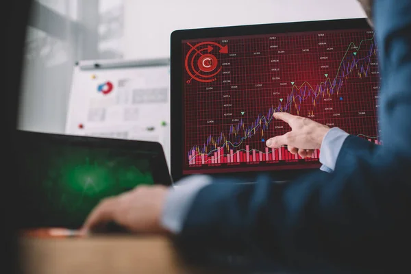 Selective focus of data analyst pointing with finger at charts on computer monitor at table — Stock Photo