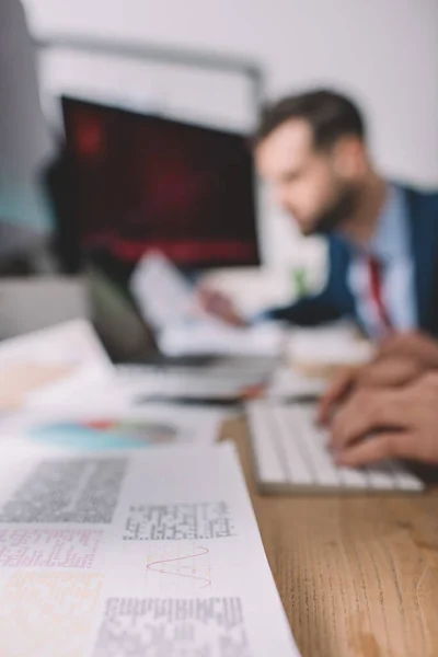 Selective focus of paper with information and data analysts working with computers at table — Stock Photo