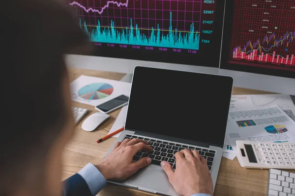 Selective focus of data analyst using laptop near charts on papers and computer monitors on table — Stock Photo