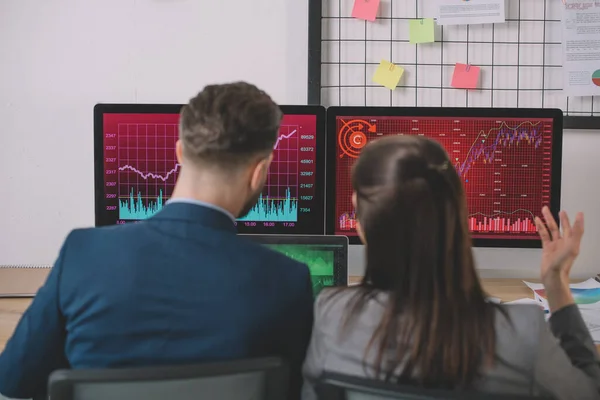 Back view of data analysts working on strategy of security with graphs on computer monitors — Stock Photo