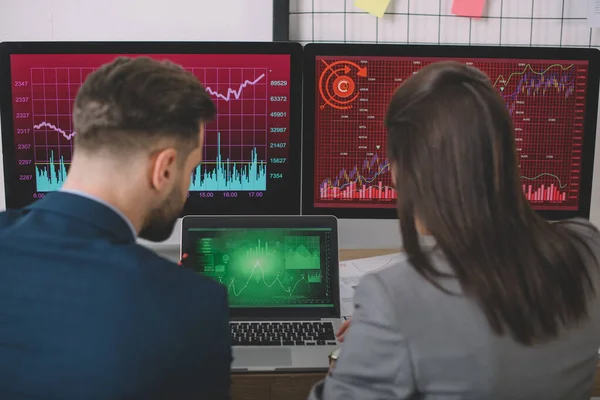 Back view of analysts working on vulnerability of computer systems with charts on computer monitors — Stock Photo