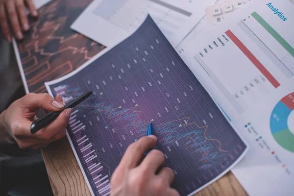 Cropped view of data analysts working with charts and papers on table — Stock Photo