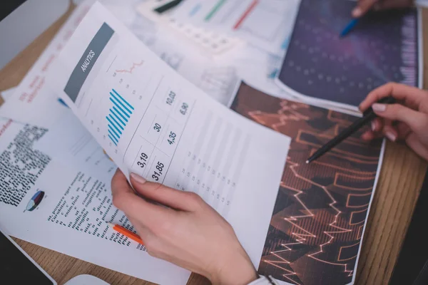 Selektiver Fokus von Analysten, die während der Arbeit am Tisch Papiere mit Diagrammen verwenden — Stockfoto