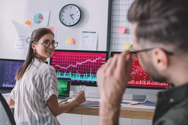 Selective focus of smiling information security analyst smiling at colleague while working in office — Stock Photo