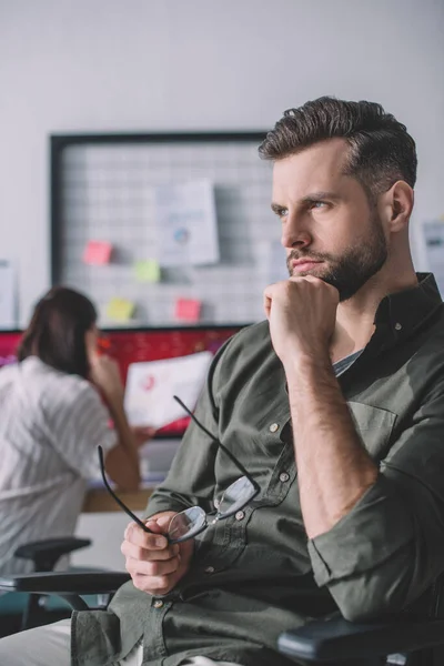 Selective focus of computer systems analyst looking away while colleague working in office — Stock Photo