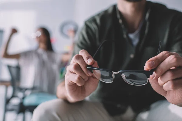 Selective focus of data analyst holding eyeglasses in office — Stock Photo