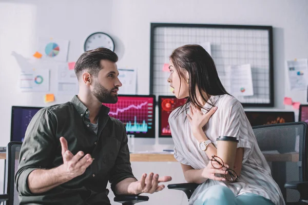 Data analyst talking to shocked colleague with paper cup in office — Stock Photo