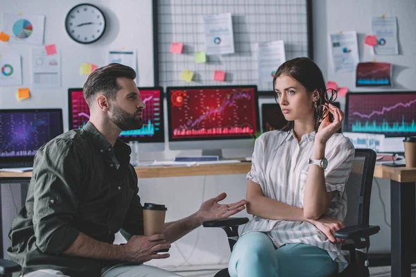 Data analyst with coffee to go talking to colleague near computers in office — Stock Photo