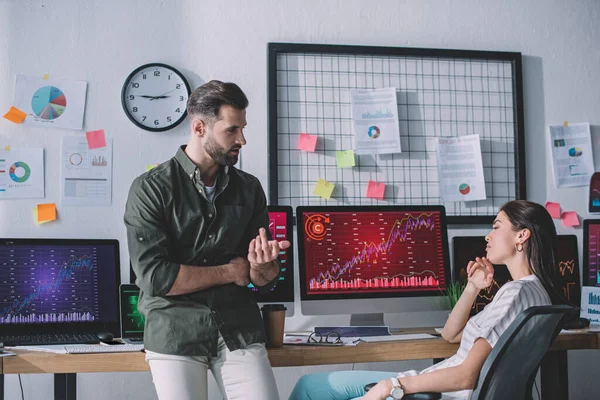 Computer systems analysts planning strategy near charts on computer monitors on table — Stock Photo