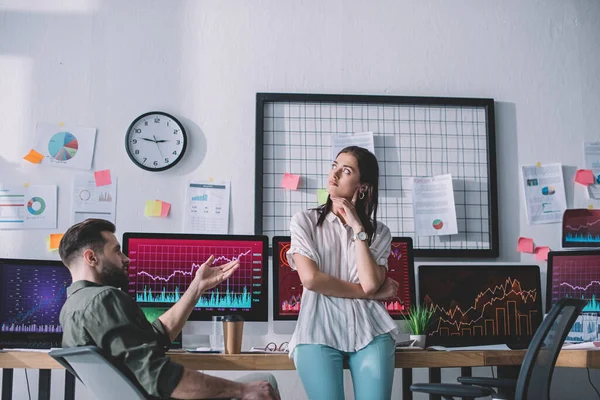 Data analyst looking at pensive colleague near computers in office — Stock Photo