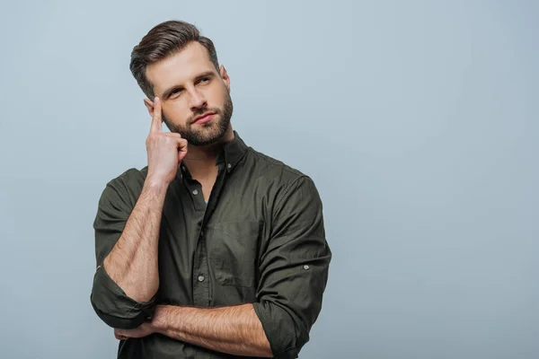 Uomo pensieroso con dito vicino alla testa guardando lontano isolato sul grigio — Foto stock