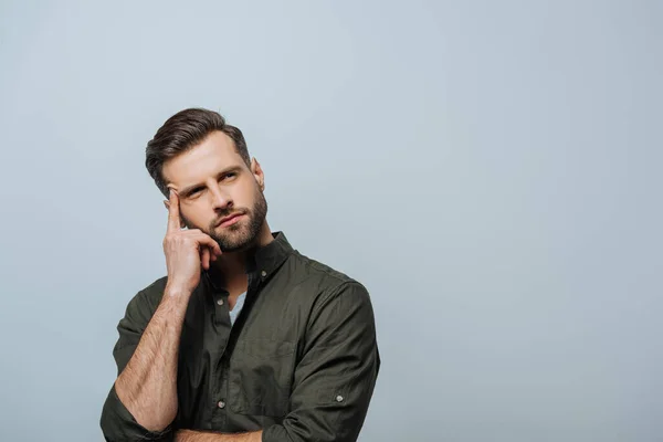 Verträumter Mann mit Finger nahe der Stirn, der isoliert auf grau blickt — Stockfoto