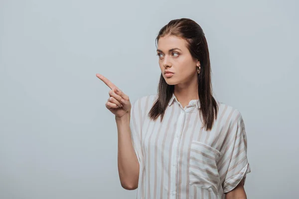 Bella giovane donna che punta con il dito isolato sul grigio — Foto stock