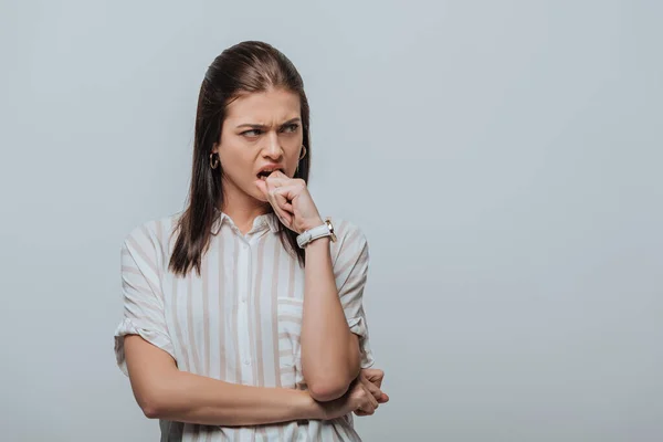 Mujer enojada con la mano cerca de la boca mirando hacia otro lado aislado en gris - foto de stock