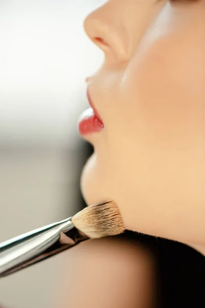 Selective focus of cosmetic brush near model with red lips — Stock Photo