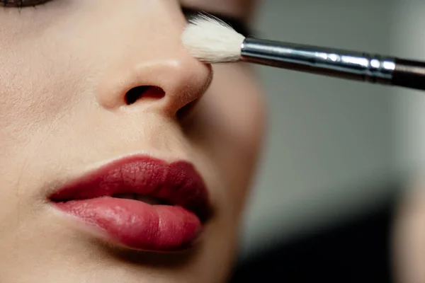 Selective focus of cosmetic brush near woman with red lips — Stock Photo