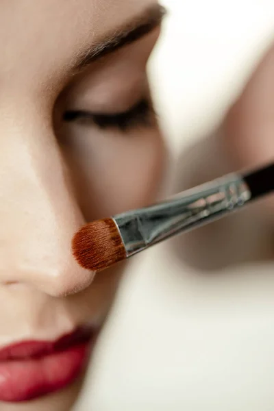 Foyer sélectif de brosse cosmétique près de la femme avec les yeux fermés — Photo de stock