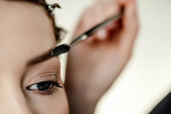 Cropped view of makeup artist styling eyebrow of woman — Stock Photo