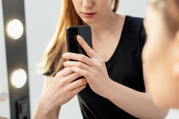 Selective focus of makeup artist taking photo of model while using smartphone — Stock Photo