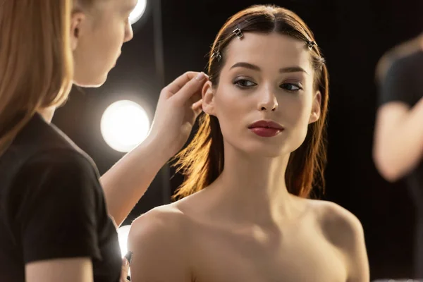 Selective focus of makeup artist touching hair of young model — Stock Photo