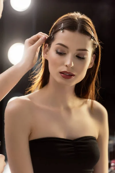 Maquillaje artista tocando el pelo de hermosa modelo - foto de stock