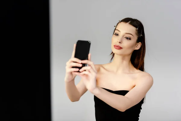 Hermosa mujer tomando selfie en gris y negro - foto de stock