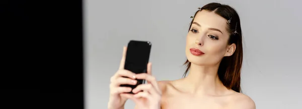 Panoramaaufnahme einer schönen Frau, die ein Selfie auf grau und schwarz macht — Stockfoto