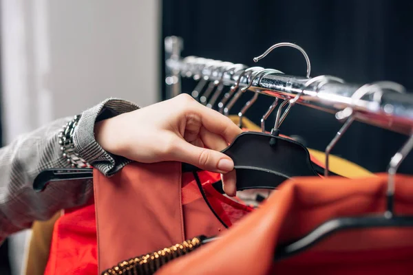 Cropped view of stylist taking hanger with clothing — Stock Photo