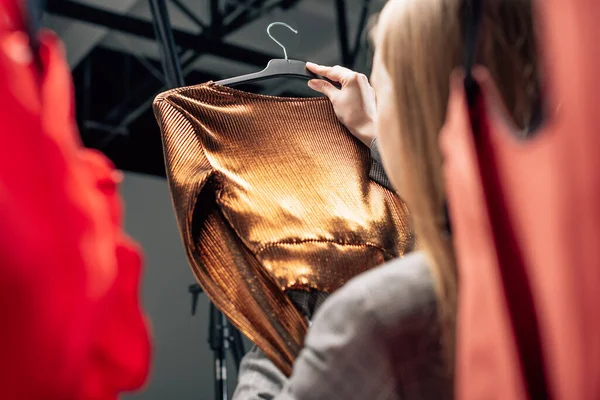 Selektiver Fokus der Stylistin mit trendiger Bluse auf Kleiderbügel — Stockfoto