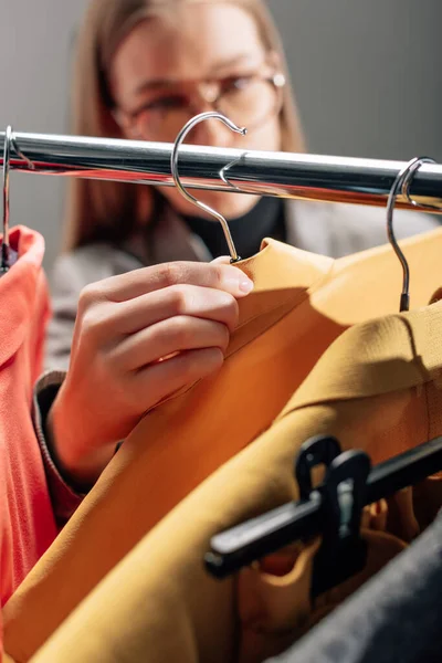 Selective focus of stylist taking hanger with fashionable clothing — Stock Photo