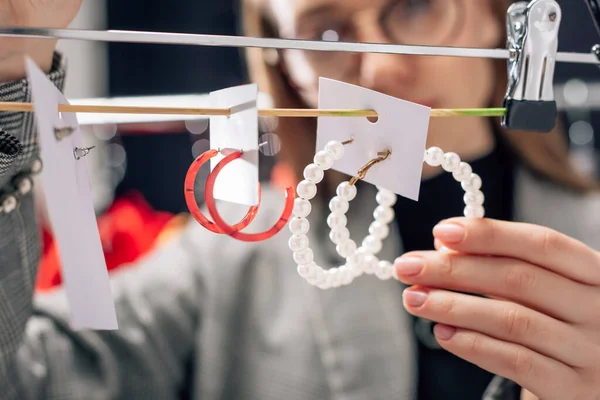 Selective focus of attractive stylist looking at earrings — Stock Photo