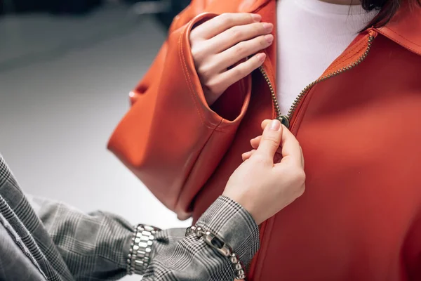 Cropped view of stylist fastening zipper on jacket of model — Stock Photo