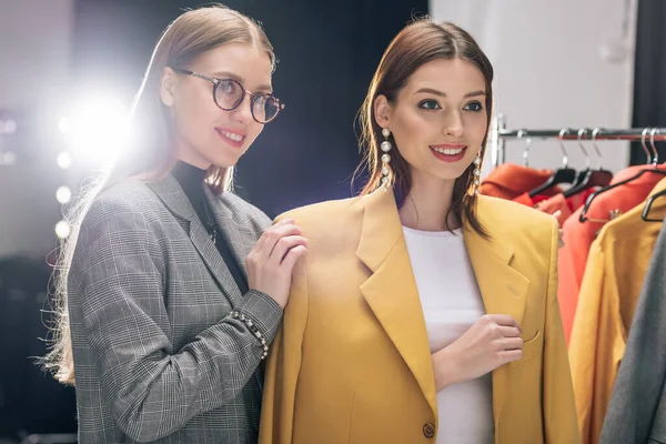 Estilista feliz en gafas de pie con modelo en pendientes - foto de stock