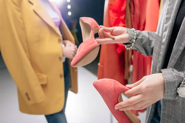 Cropped view of stylist holding shoes near model in blazer — Stock Photo